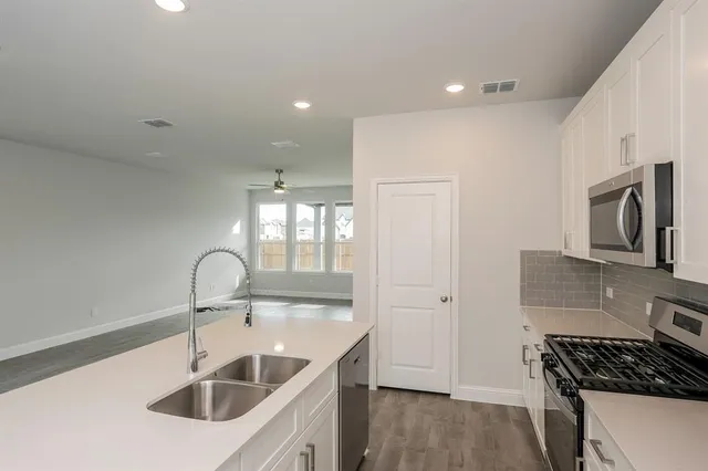 a kitchen with microwave a stove and white cabinets