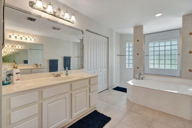 a spacious bathroom with a tub sink and mirror