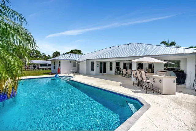 a front view of a house with swimming pool having outdoor seating