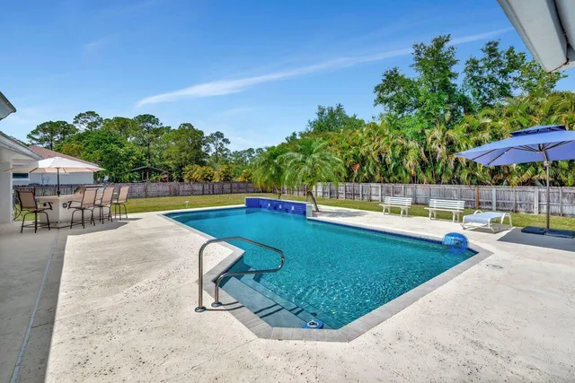 a view of a swimming pool with a patio and a yard