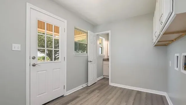 a view of an empty room with wooden floor and a window
