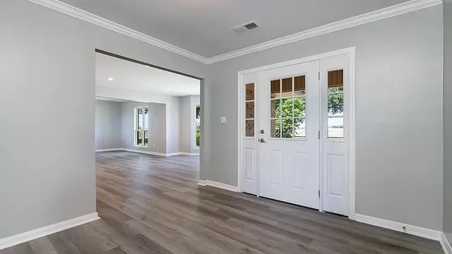 an empty room with wooden floor and windows