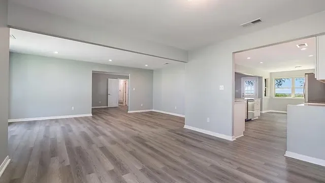 a view of a big room with wooden floor and a kitchen