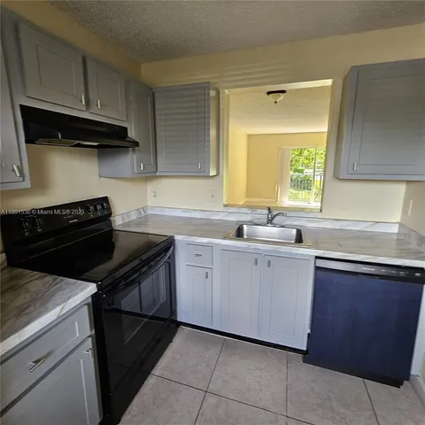 a kitchen with cabinets appliances a sink and a window