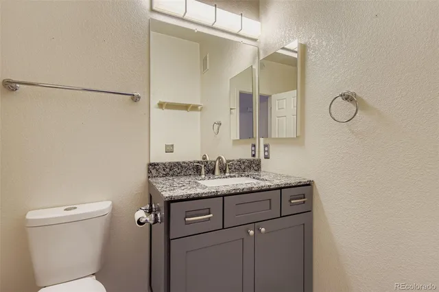 a bathroom with a granite countertop sink a toilet and a mirror