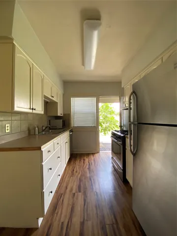 a kitchen with granite countertop a refrigerator a sink a stove a microwave and wooden floor