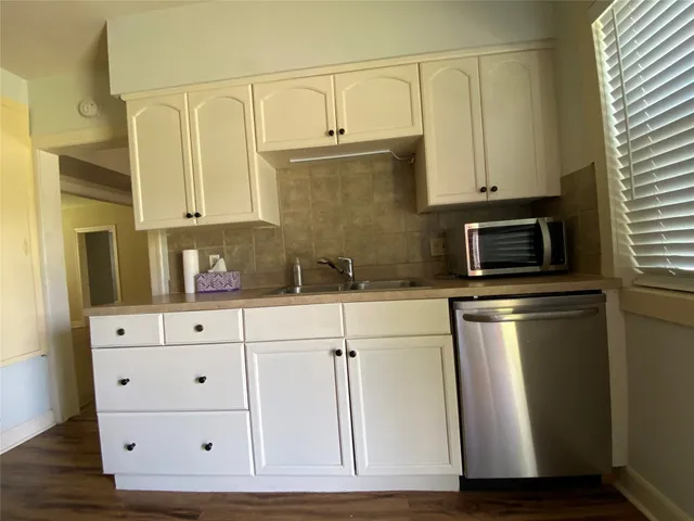 a kitchen with granite countertop white cabinets and stainless steel appliances