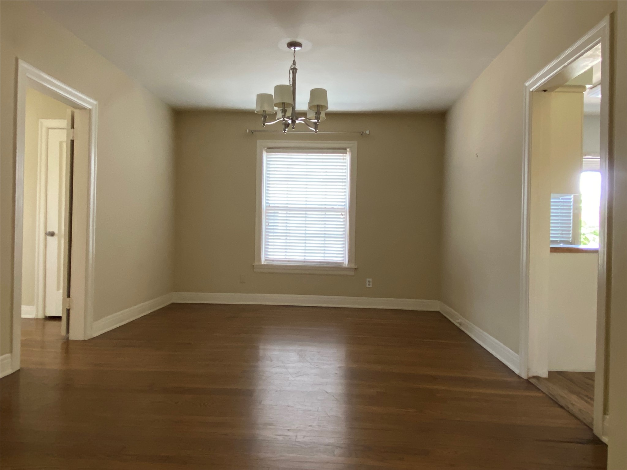 1918 Sul Ross Street, Unit B Houston, TX 77098 - Photo 9 of 17 an empty room with wooden floor chandelier and windows