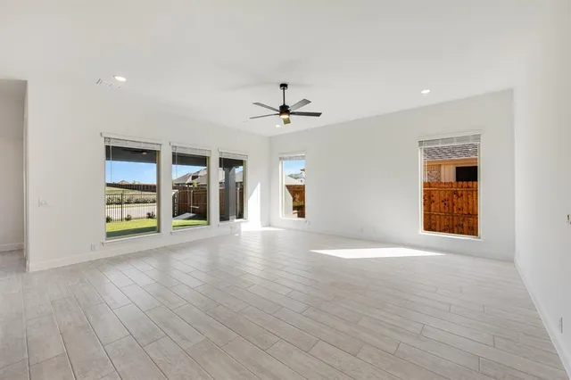 a view of an empty room with a window and a kitchen
