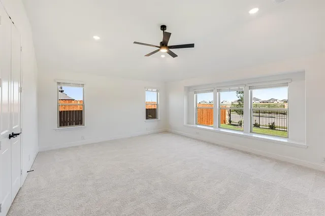 an empty room with windows and ceiling fan