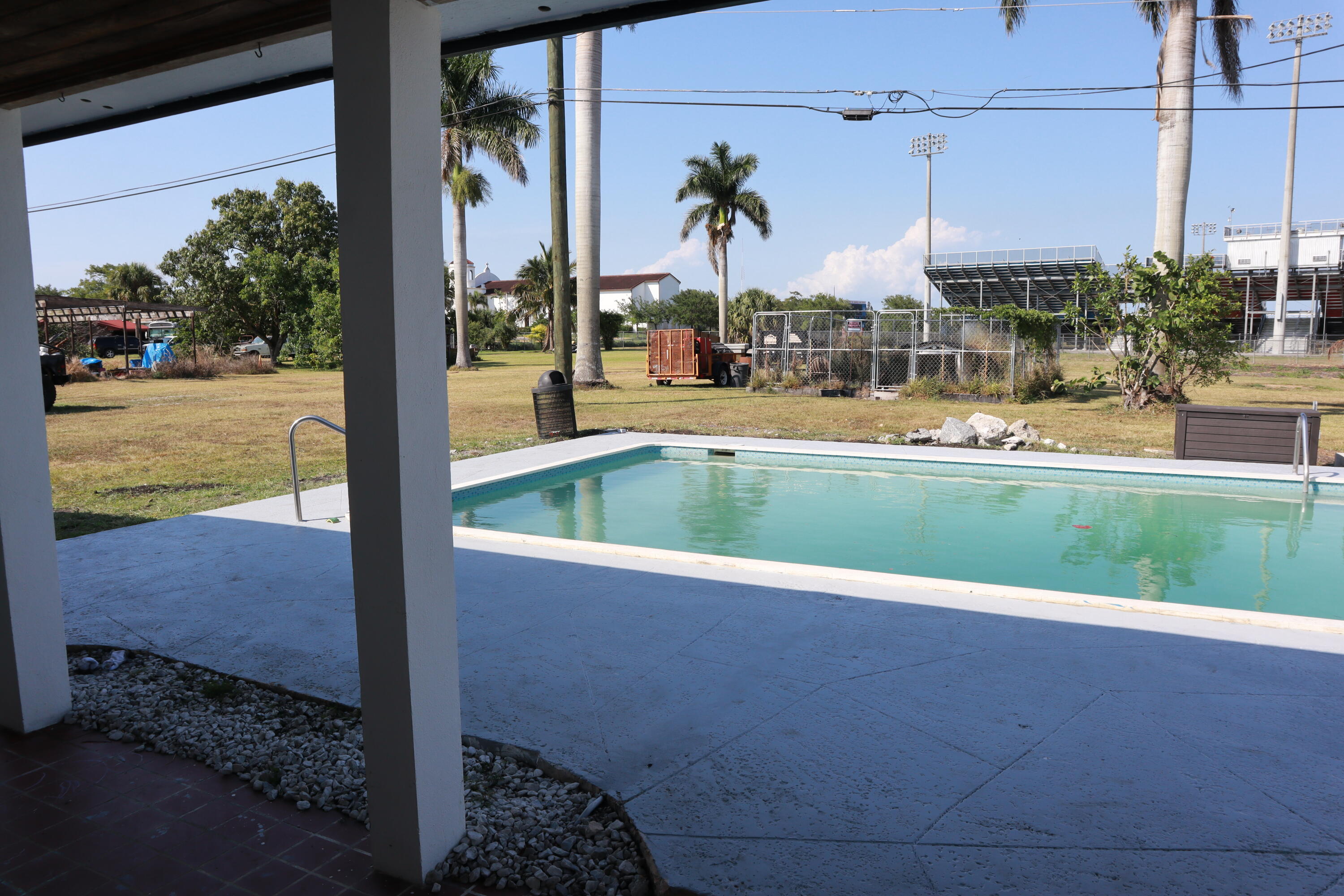360 Kismet Avenue Pahokee, FL 33476 - Photo 84 of 100 a view of a swimming pool with a lawn chairs under an umbrella