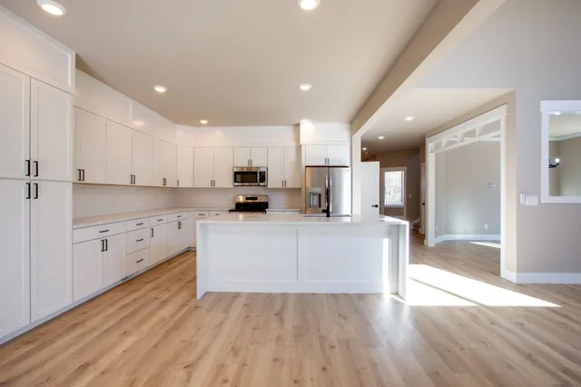 a large white kitchen with white cabinets and wooden floor