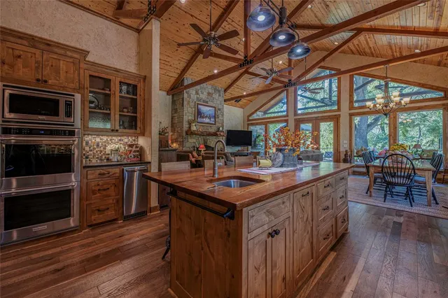 a kitchen with stainless steel appliances granite countertop a stove a refrigerator a sink and a dining table with wooden floor