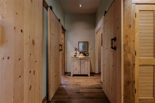 a view of a hallway with wooden floor and a bathroom
