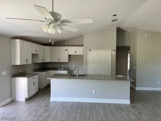 a kitchen with stainless steel appliances granite countertop a sink a stove and a wooden floors