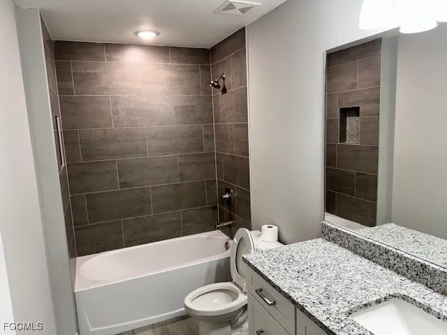 a bathroom with a granite countertop sink a toilet and bathtub