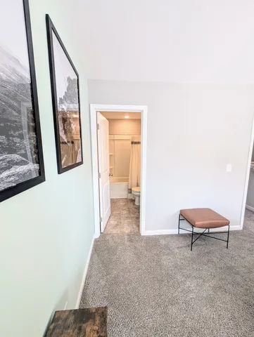 a view of a hallway with wooden floor and a bathroom