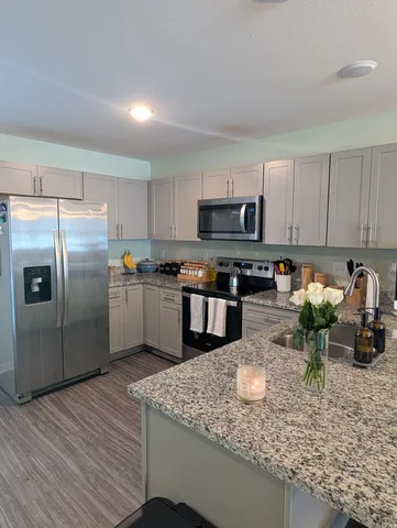 a kitchen with stainless steel appliances granite countertop a sink a stove and a microwave with wooden floor