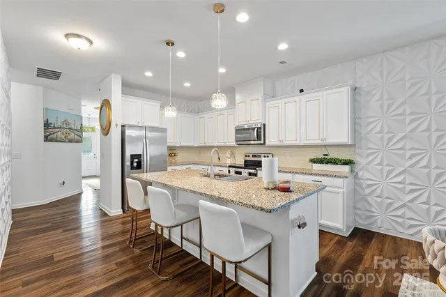 a large kitchen with stainless steel appliances granite countertop a stove a sink and a refrigerator