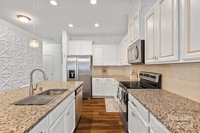 a large kitchen with stainless steel appliances granite countertop a table chairs sink and cabinets