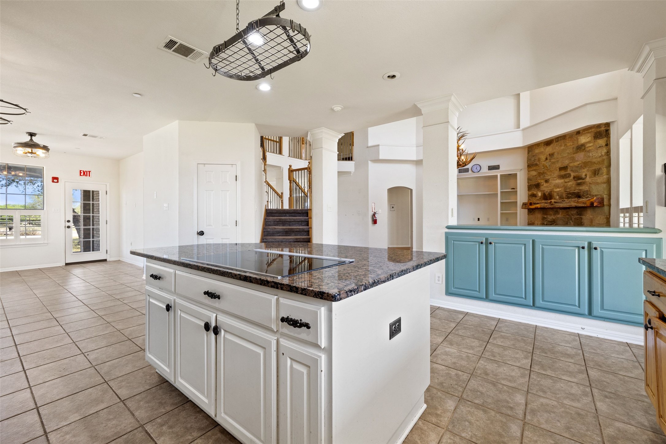 815 Elliott Ranch Road Buda, TX 78610 - Photo 39 of 40 Kitchen with a center island, light tile patterned flooring, black electric stovetop, dark stone counters, and open floor plan