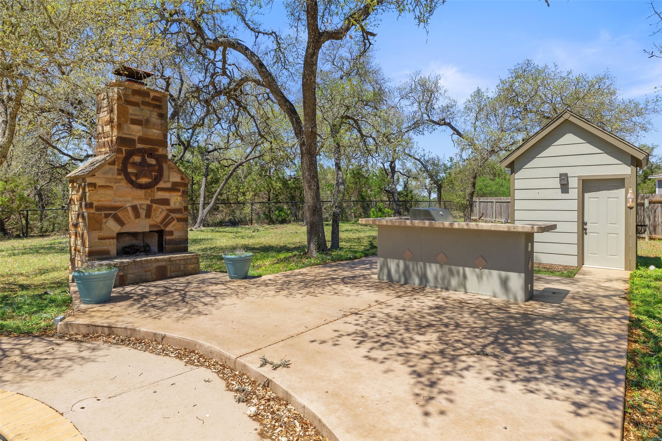 815 Elliott Ranch Road Buda, TX 78610 - Photo 26 of 40 Fenced backyard with an outdoor stone fireplace and a patio area
