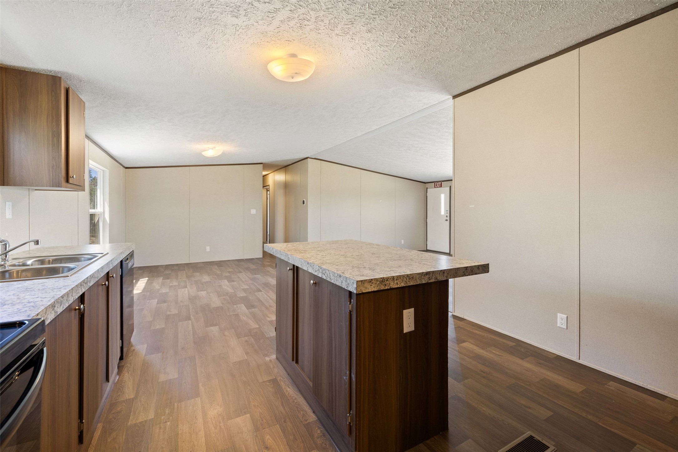 815 Elliott Ranch Road Buda, TX 78610 - Photo 35 of 40 Kitchen in mobil home with dark wood finish cabinets, dark wood-style flooring, a textured ceiling, light countertops, and a kitchen island