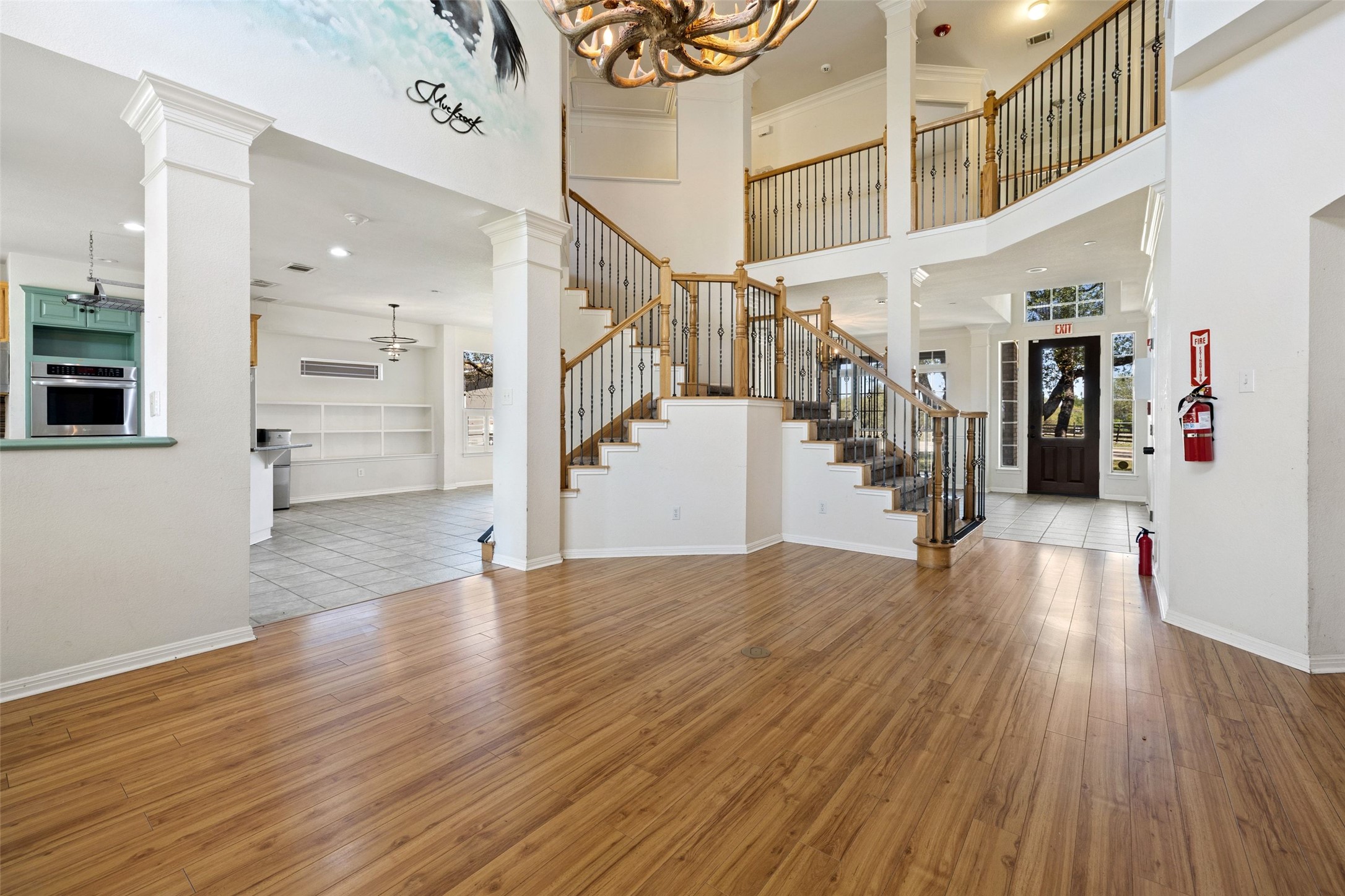 815 Elliott Ranch Road Buda, TX 78610 - Photo 7 of 40 living room with hardwood / wood-style flooring, ornate columns, suspended lighting, and a high ceiling