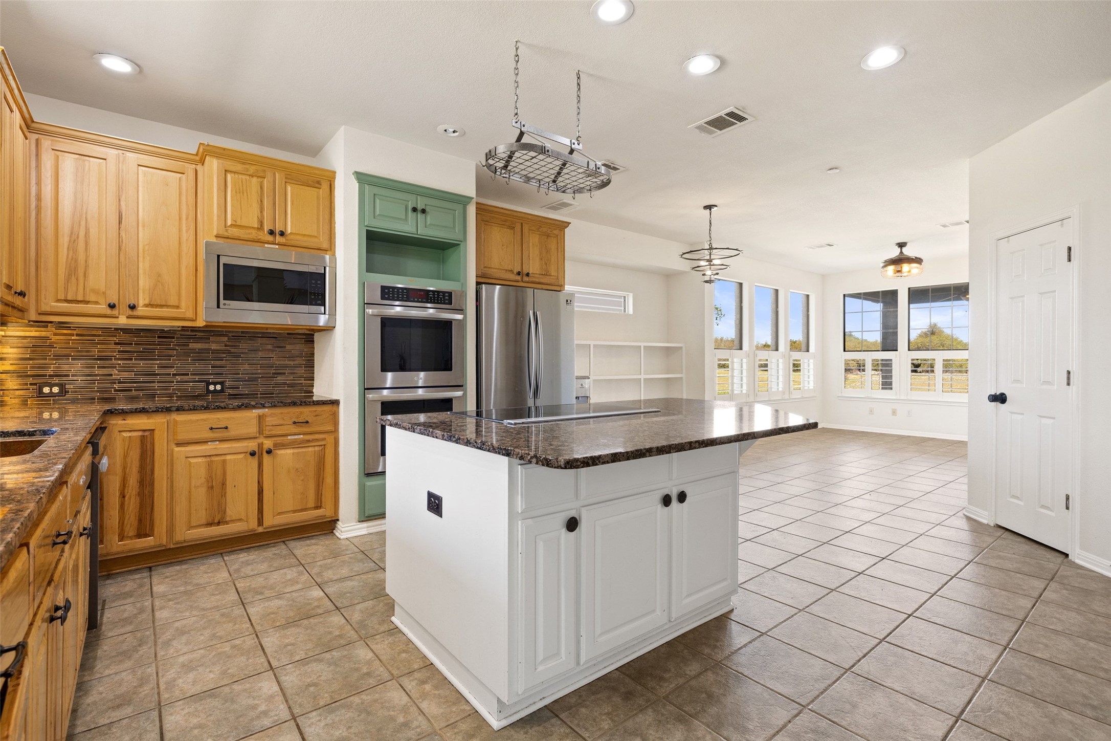 815 Elliott Ranch Road Buda, TX 78610 - Photo 8 of 40 Kitchen featuring dark stone countertops, stainless steel appliances, light tile patterned flooring, and a kitchen island