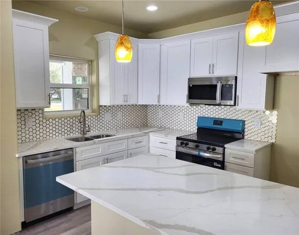 a kitchen with stainless steel appliances granite countertop a stove a sink and a microwave