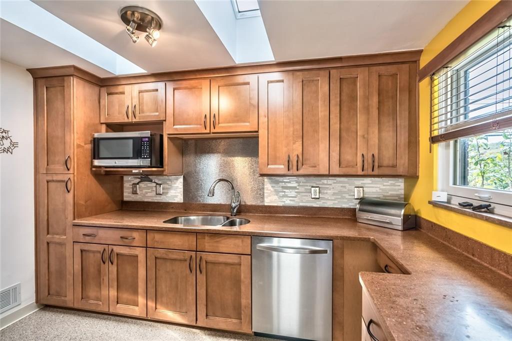9101 Pannier Road Pittsburgh, PA 15237 - Photo 15 of 24 Eat-in Kitchen beautifully renovated with 2 Skylights, Maple Cabinetry, Under Cabinet Lighting, Corian Countertops, sleek new Flooring, Tile Backsplash, Electric Range, Refrigerator, Dishwasher & Microwave Oven