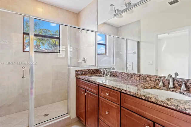 a bathroom with a granite countertop sink a mirror a shower and vanity
