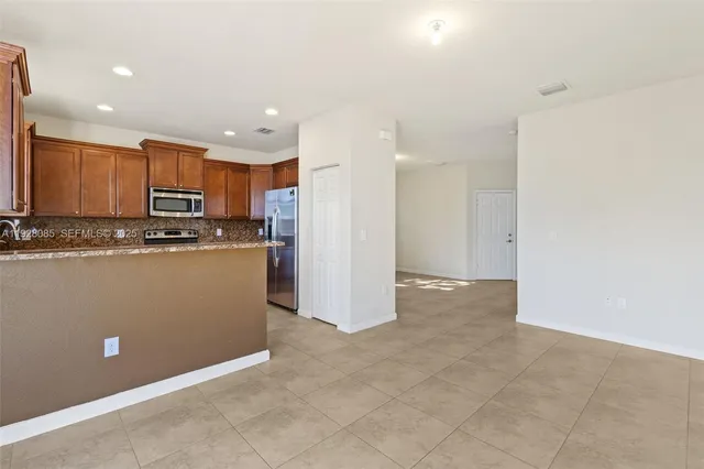 a kitchen with stainless steel appliances granite countertop a refrigerator a stove top oven and a sink with wooden floor