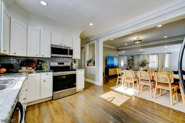 a kitchen with stainless steel appliances granite countertop a stove top oven a sink dishwasher a dining table and chairs with wooden floor