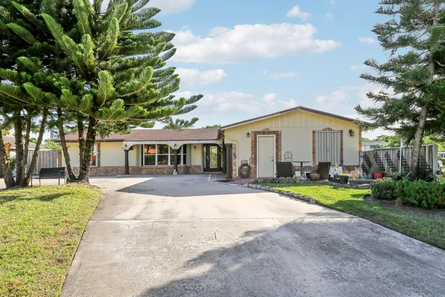 a front view of a house with a yard and potted plants