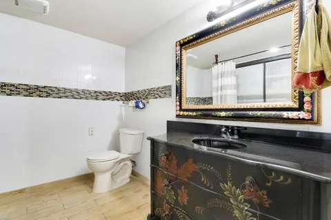 a bathroom with a granite countertop sink a toilet and a mirror