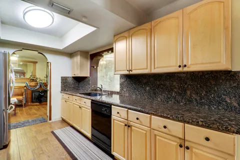 a kitchen with granite countertop a sink a stove and cabinets