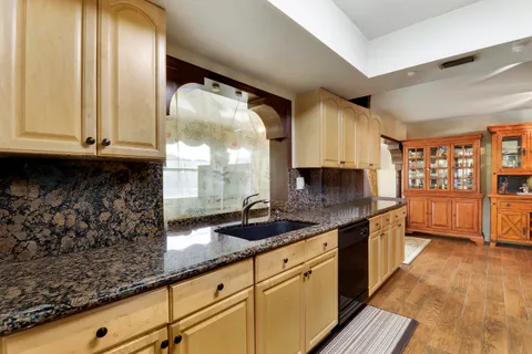 a kitchen with granite countertop a sink and a white wooden cabinets