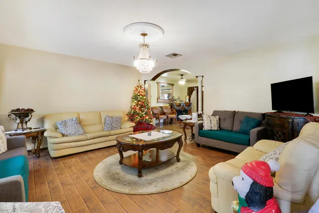 a living room with furniture a flat screen tv and floor to ceiling window