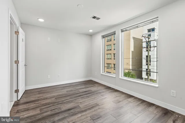 a view of an empty room with wooden floor and a window