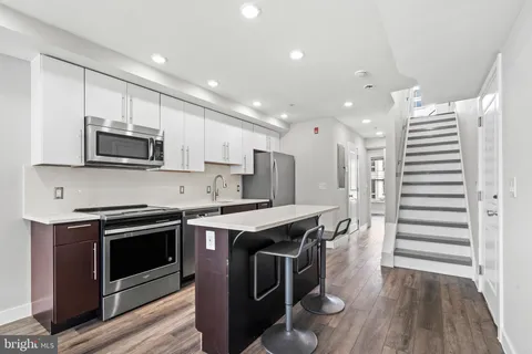 a kitchen with stainless steel appliances a stove a sink a microwave a refrigerator and cabinets