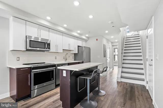 a kitchen with stainless steel appliances a stove a sink a microwave a refrigerator and cabinets