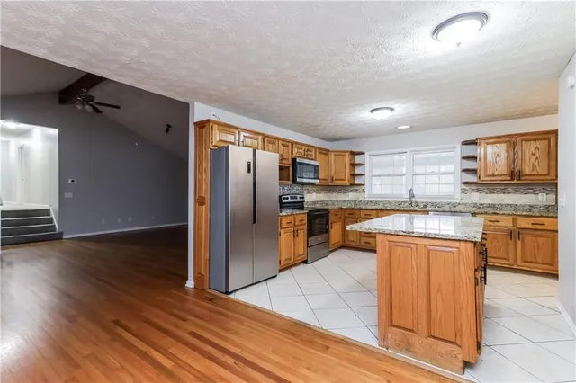 a kitchen with stainless steel appliances granite countertop a refrigerator and a stove top oven