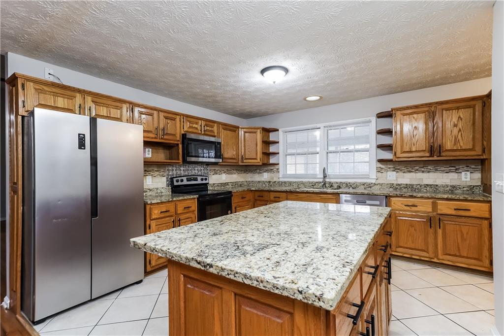35 Knights Circle Covington, GA 30016 - Photo 4 of 28 a kitchen with stainless steel appliances granite countertop a refrigerator a oven a sink with island and chairs