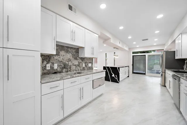 a large white kitchen with stainless steel appliances large white cabinets and a refrigerator