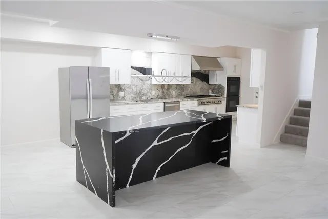 a living room with stainless steel appliances furniture a refrigerator and cabinets