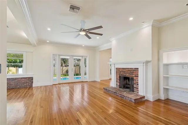 a view of an empty room with wooden floor fireplace and a window