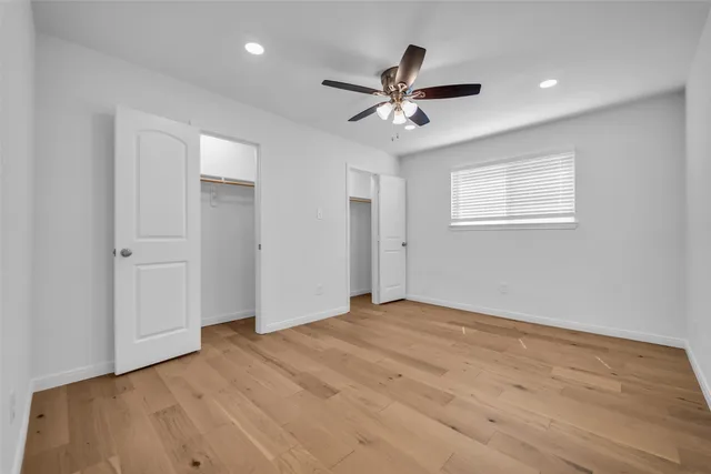 a view of empty room with wooden floor and fan