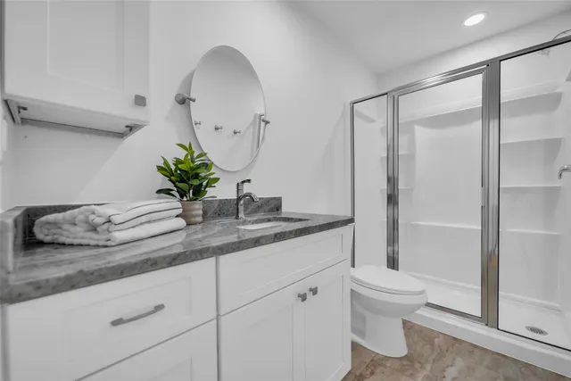 a bathroom with a granite countertop sink a toilet and shower