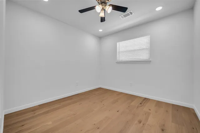 an empty room with a ceiling fan and wooden floor
